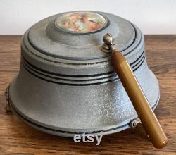 Vintage metal musical powder box with butterscotch bakelite handle and porcelain medallion lid