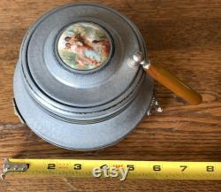 Vintage metal musical powder box with butterscotch bakelite handle and porcelain medallion lid