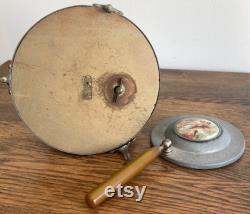 Vintage metal musical powder box with butterscotch bakelite handle and porcelain medallion lid